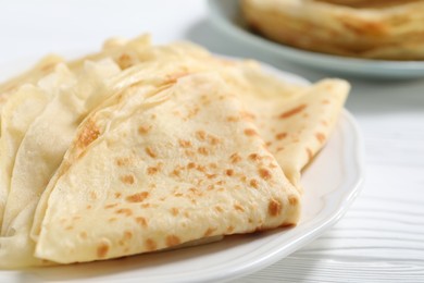 Photo of Tasty crepes on white wooden table, closeup