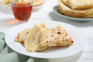 Photo of Tasty crepes on white wooden table, closeup