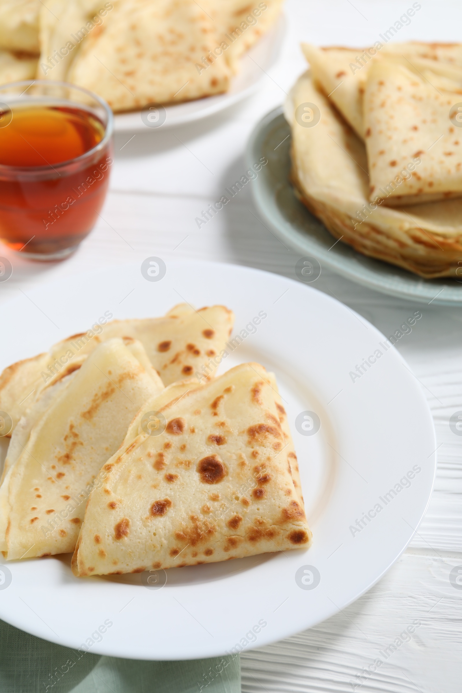 Photo of Tasty crepes on white wooden table, closeup