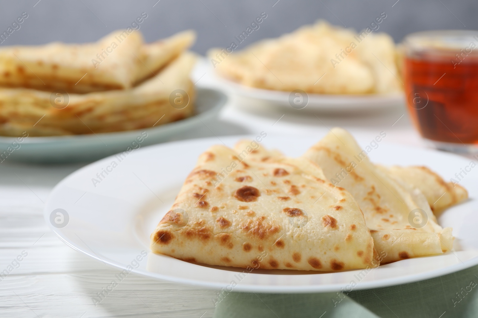 Photo of Tasty crepes on white wooden table, closeup