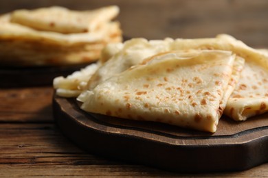 Photo of Tasty thin crepes on wooden table, closeup