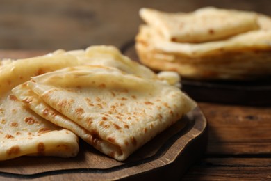 Photo of Tasty thin crepes on wooden table, closeup