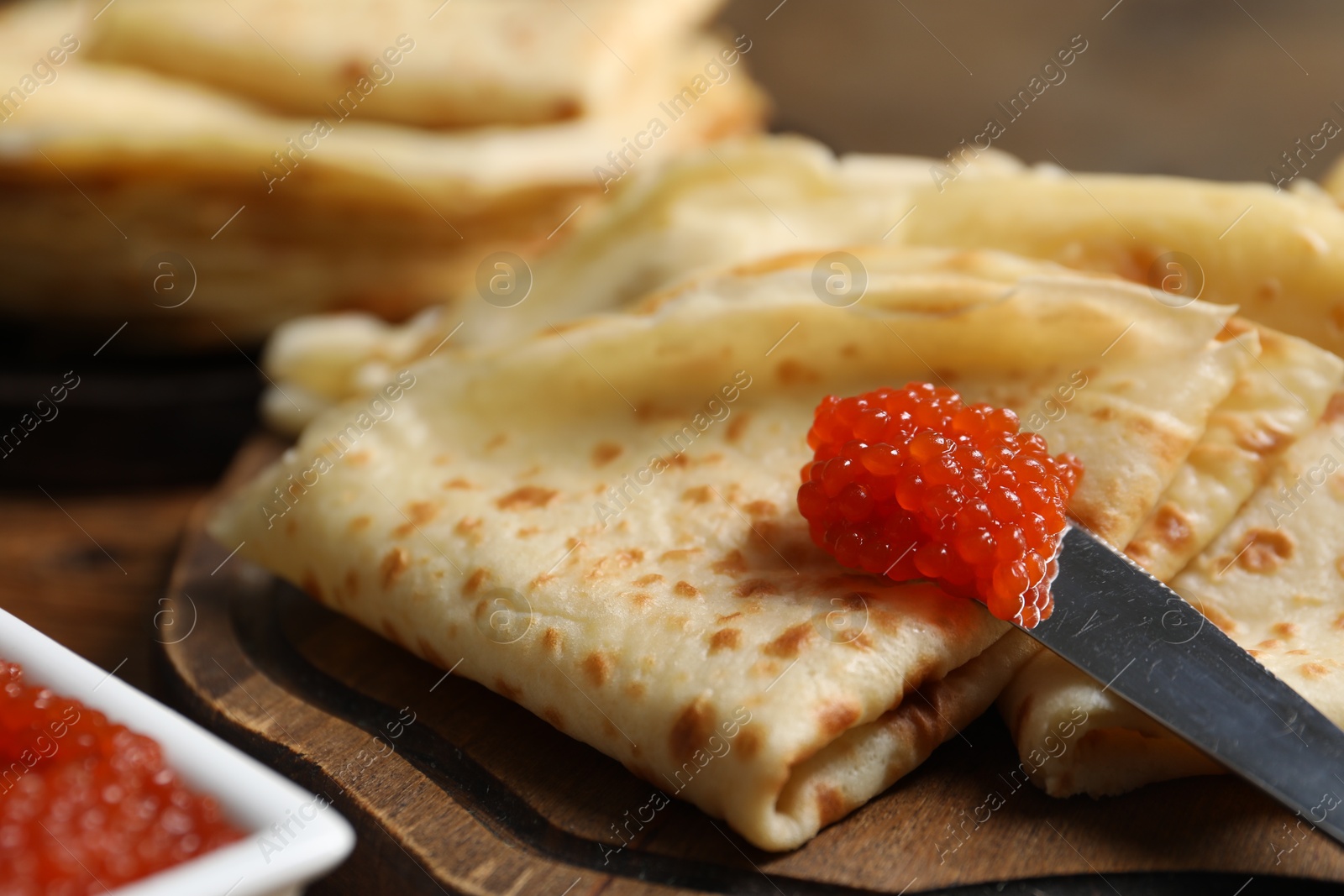 Photo of Tasty crepes and red caviar on table, closeup