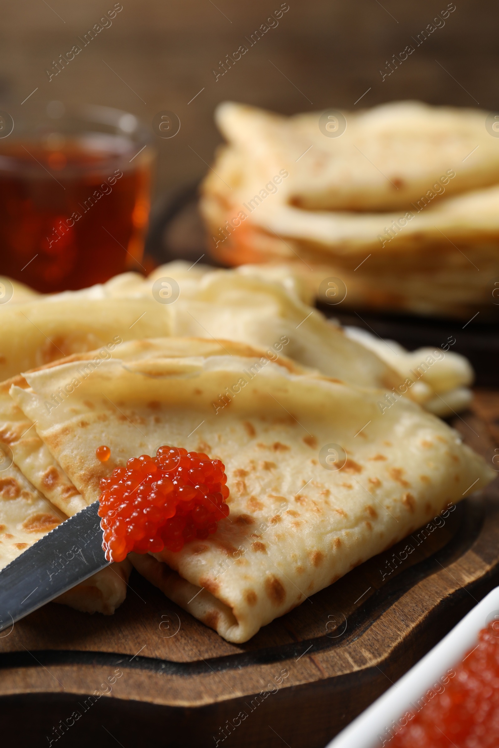 Photo of Tasty crepes and red caviar on table, closeup