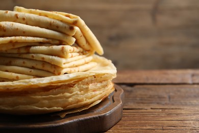 Stack of tasty crepes on wooden table, closeup. Space for text