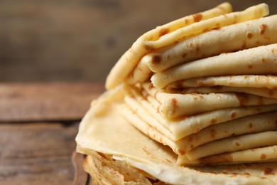 Stack of tasty crepes on wooden table, closeup. Space for text