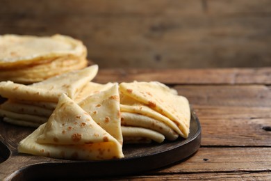 Photo of Tasty crepes on wooden table, closeup. Space for text