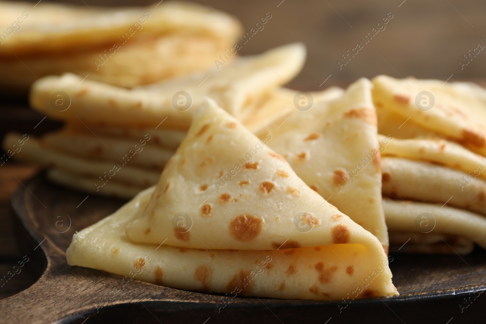 Photo of Many tasty crepes on wooden board, closeup