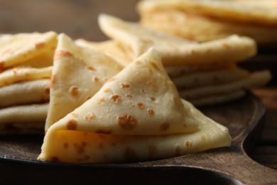 Photo of Many tasty crepes on wooden board, closeup