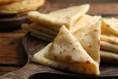 Photo of Tasty thin crepes on wooden table, closeup