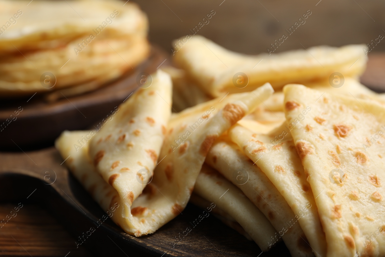 Photo of Tasty thin crepes on wooden table, closeup