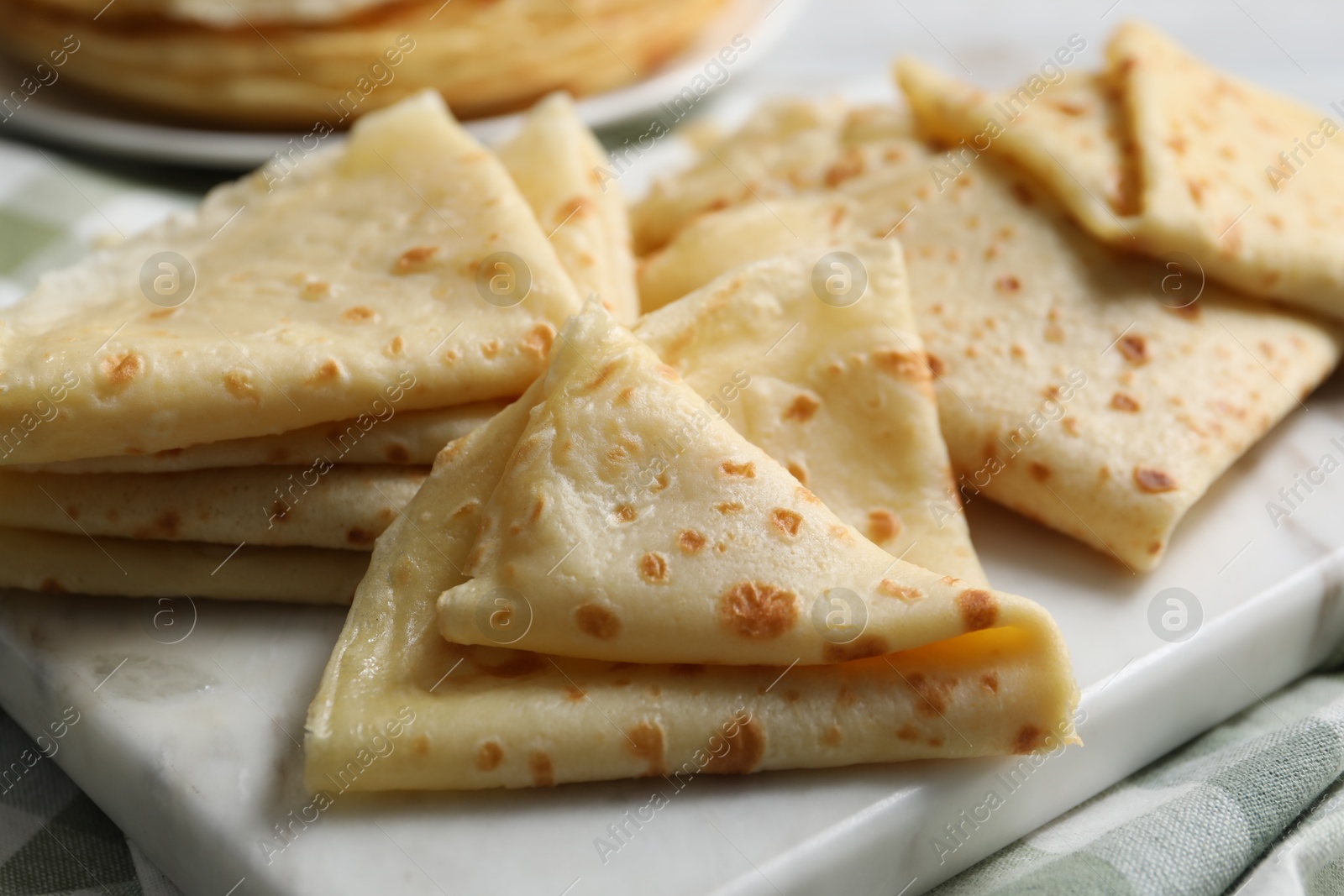 Photo of Many tasty crepes on white marble board, closeup