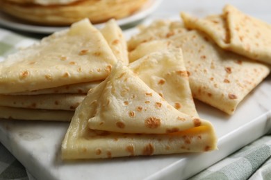 Photo of Many tasty crepes on white marble board, closeup