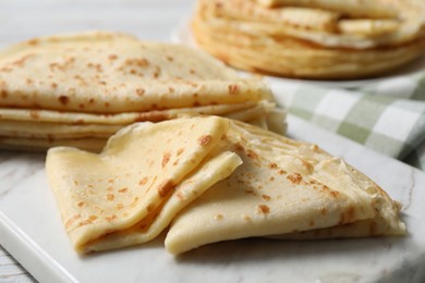 Photo of Many tasty crepes on white wooden table, closeup