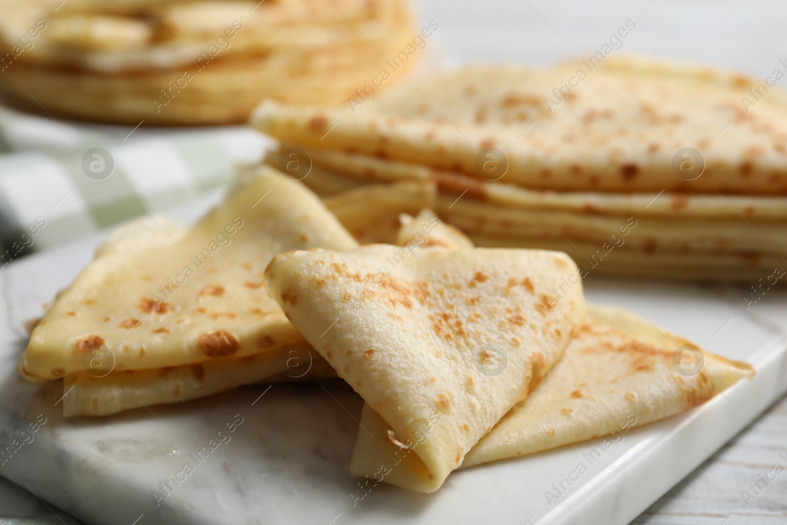 Photo of Many tasty crepes on white wooden table, closeup