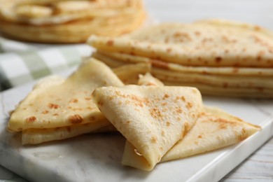 Photo of Many tasty crepes on white wooden table, closeup