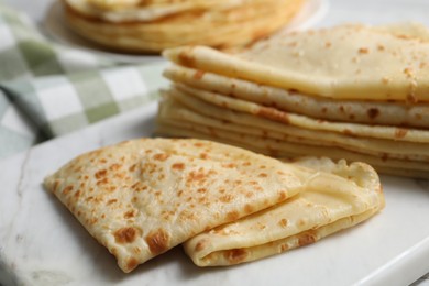 Photo of Many tasty thin crepes on table, closeup