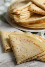 Many tasty thin crepes on table, closeup