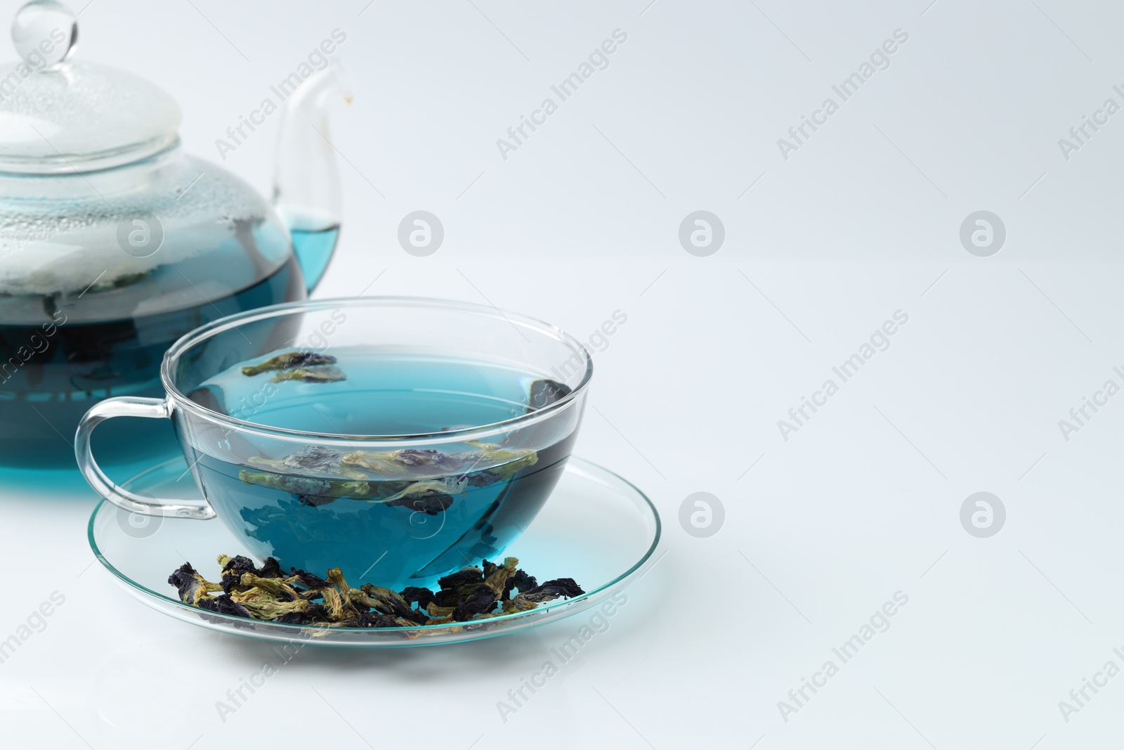 Photo of Fresh butterfly pea flower tea and dry petals on white table, closeup. Space for text