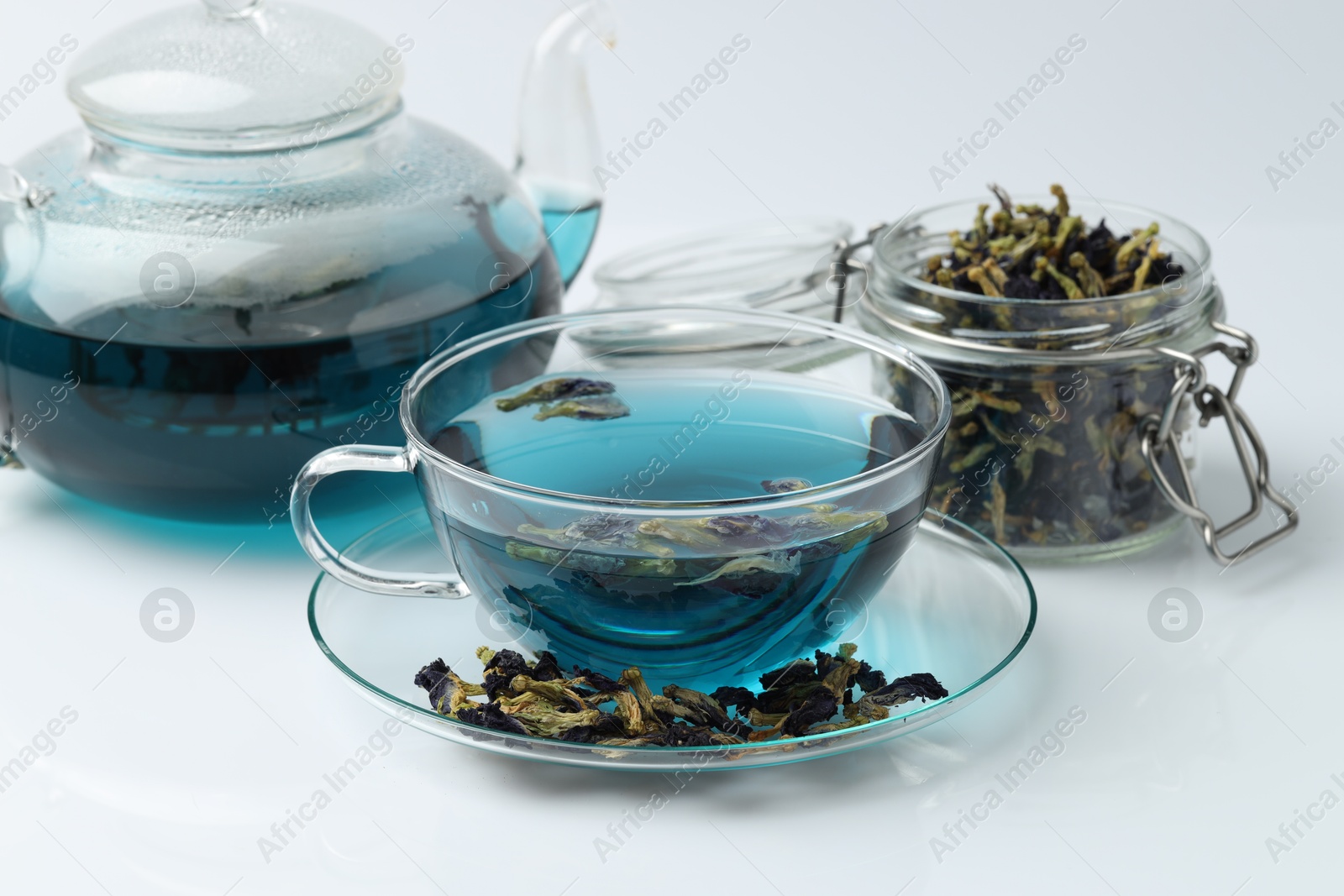 Photo of Fresh butterfly pea flower tea and dry petals on white table, closeup