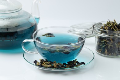 Photo of Fresh butterfly pea flower tea and dry petals on white table, closeup