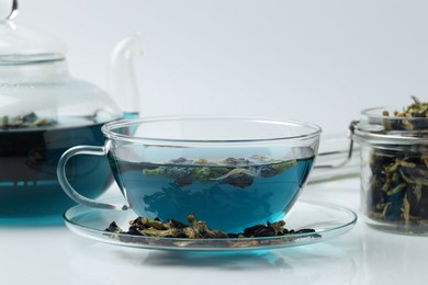 Photo of Fresh butterfly pea flower tea and dry petals on white table, closeup