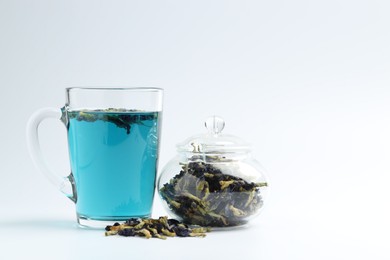 Photo of Fresh butterfly pea flower tea and dry petals on white table, closeup