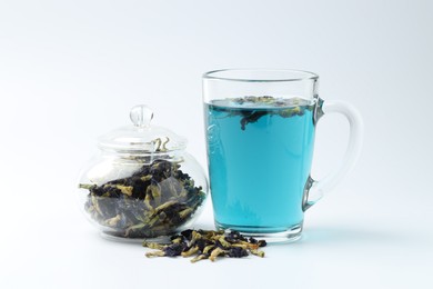 Photo of Fresh butterfly pea flower tea and dry petals on white table, closeup