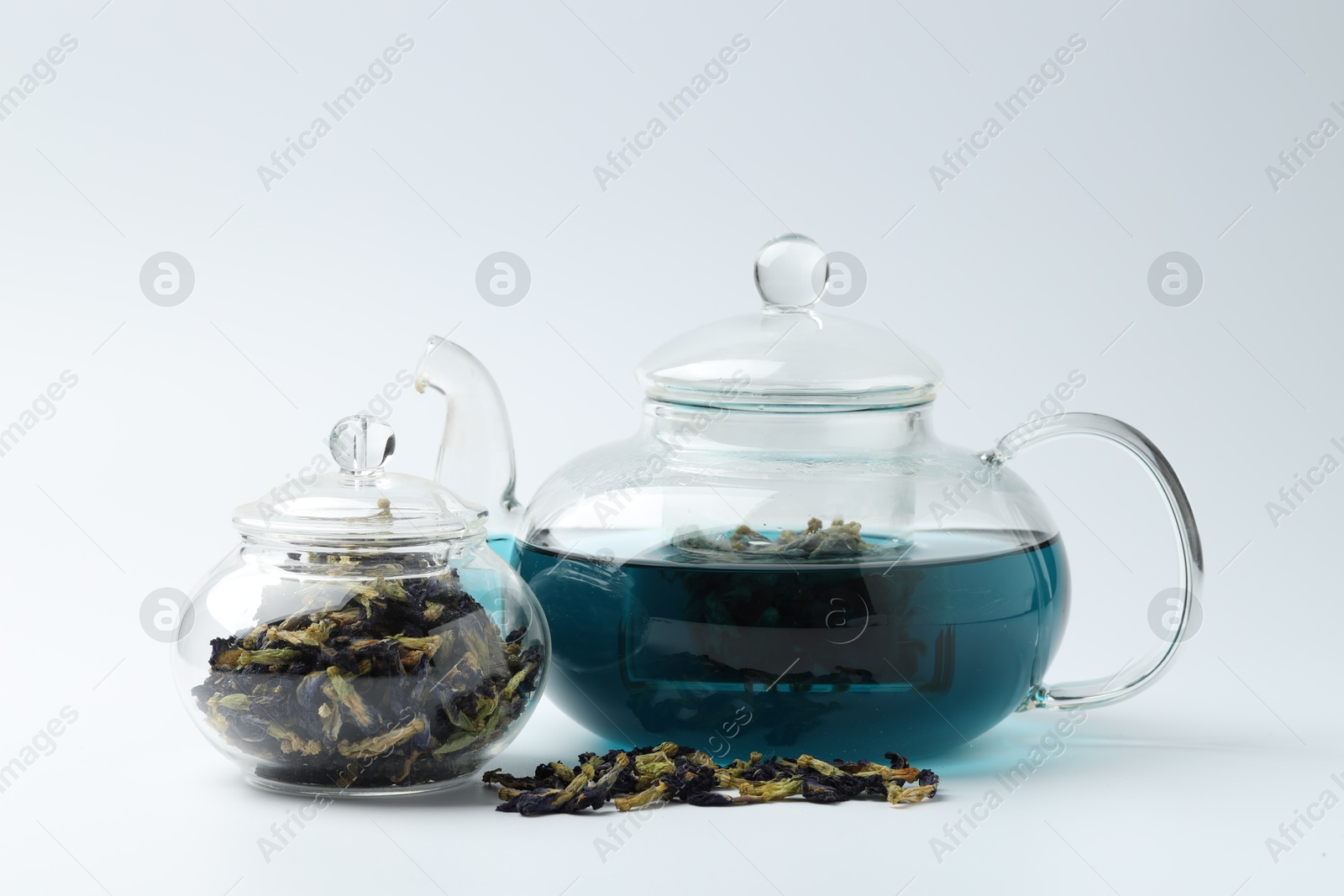 Photo of Fresh butterfly pea flower tea and dry petals on white table, closeup