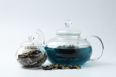 Photo of Fresh butterfly pea flower tea and dry petals on white table, closeup