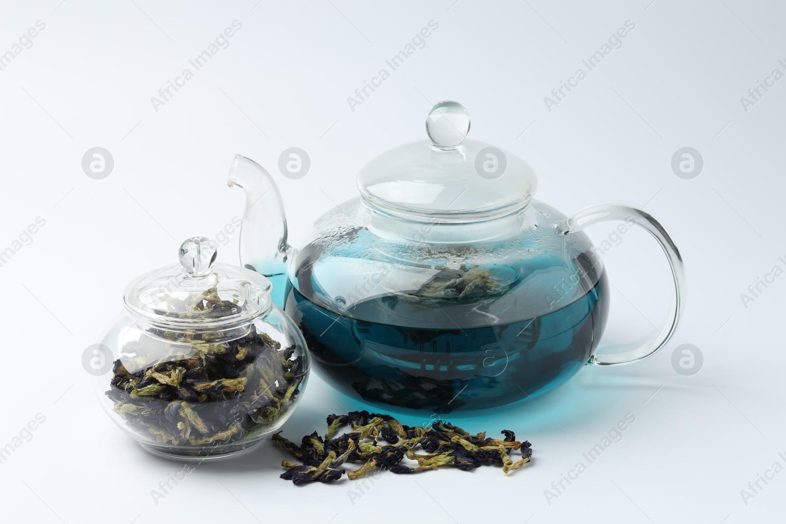 Photo of Fresh butterfly pea flower tea and dry petals on white table, closeup