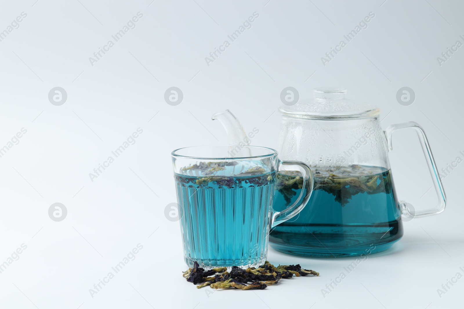 Photo of Fresh butterfly pea flower tea and dry petals on white table. Space for text