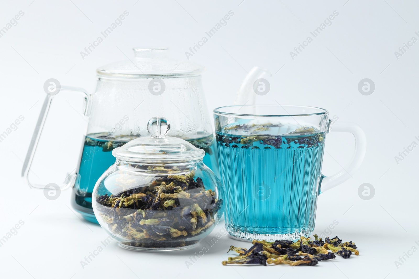 Photo of Fresh butterfly pea flower tea and dry petals on white table, closeup