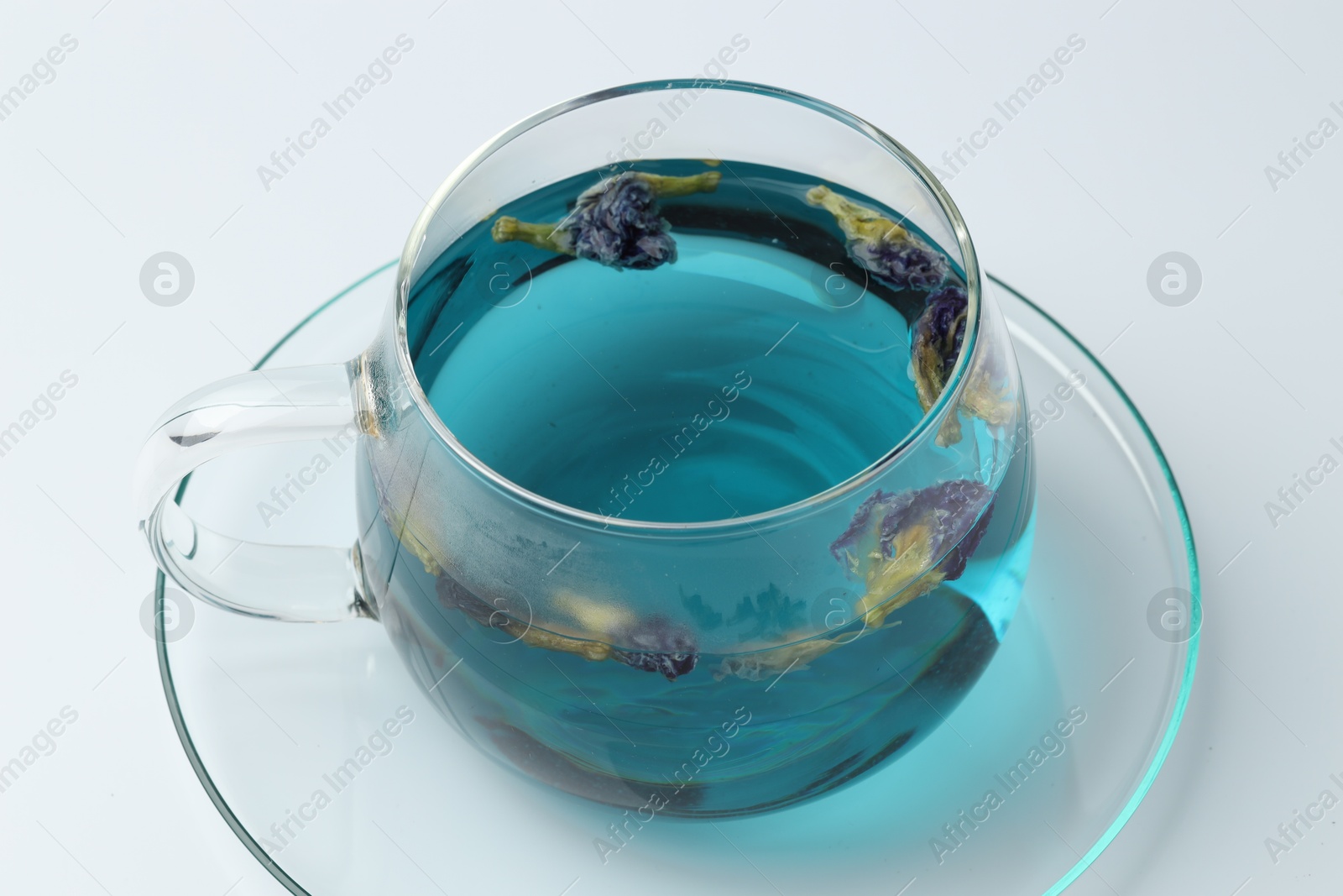 Photo of Fresh butterfly pea flower tea in cup on white table, closeup