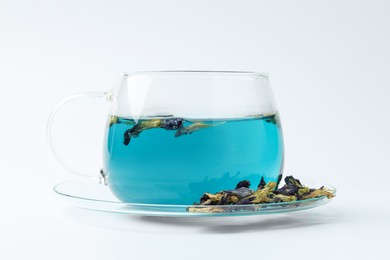 Photo of Fresh butterfly pea flower tea in cup and dry petals on white table, closeup