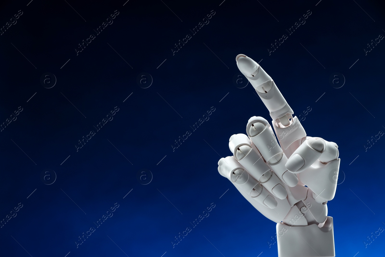 Photo of Artificial intelligence. Robot hand pointing at something on dark blue background, space for text