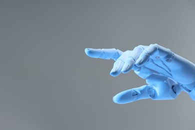 Photo of Artificial intelligence. Robot hand pointing at something on grey background, space for text