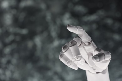 Photo of Artificial intelligence. Robot hand pointing at something on grey blurred background, space for text