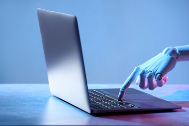 Photo of Artificial intelligence. Robot hand with laptop on table in neon lights