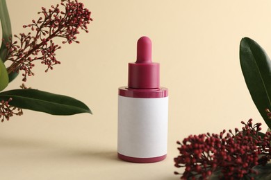 Photo of Bottle of skin care product and skimmia plant on beige background