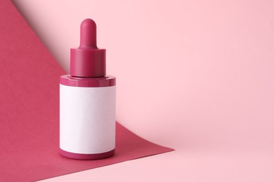 Photo of Bottle of skin care product on pink background, space for text