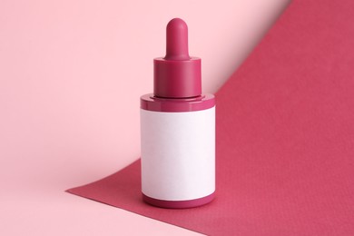 Photo of Bottle of skin care product on pink background, space for text