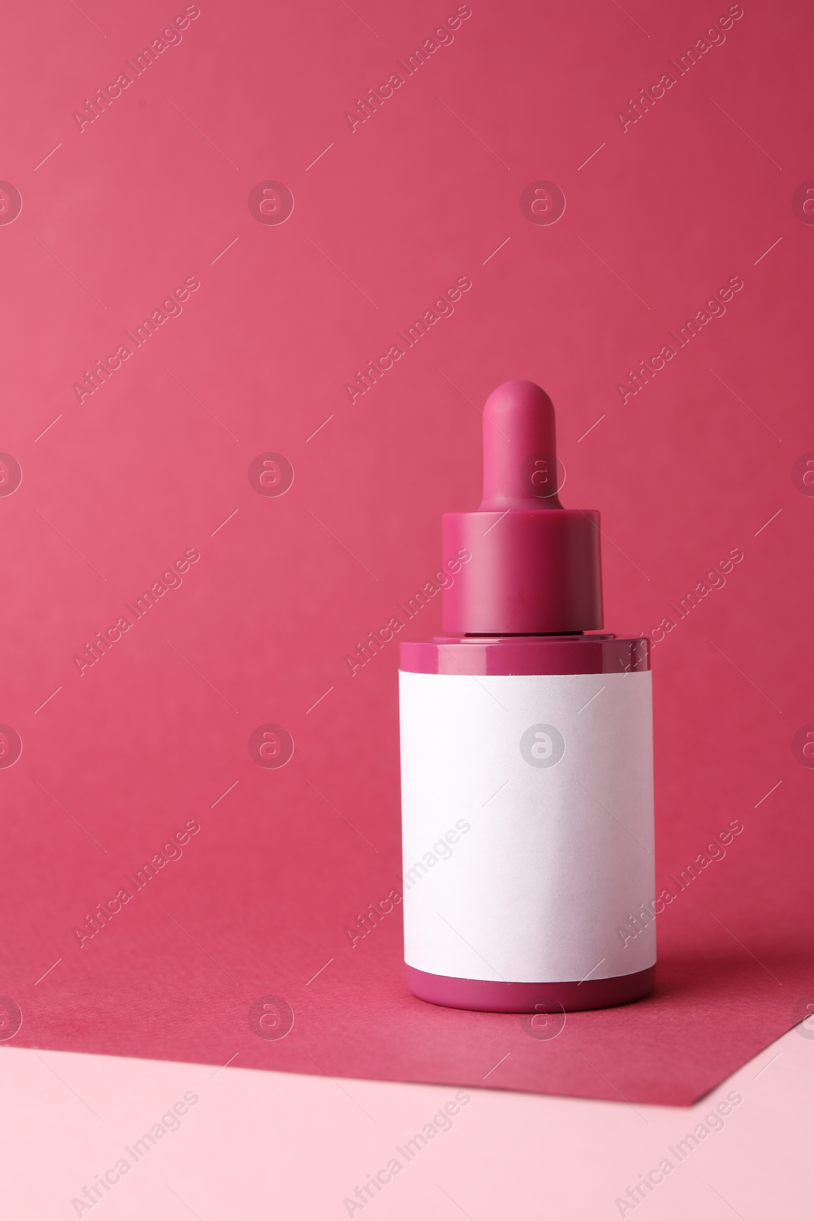 Photo of Bottle of skin care product on pink background, space for text