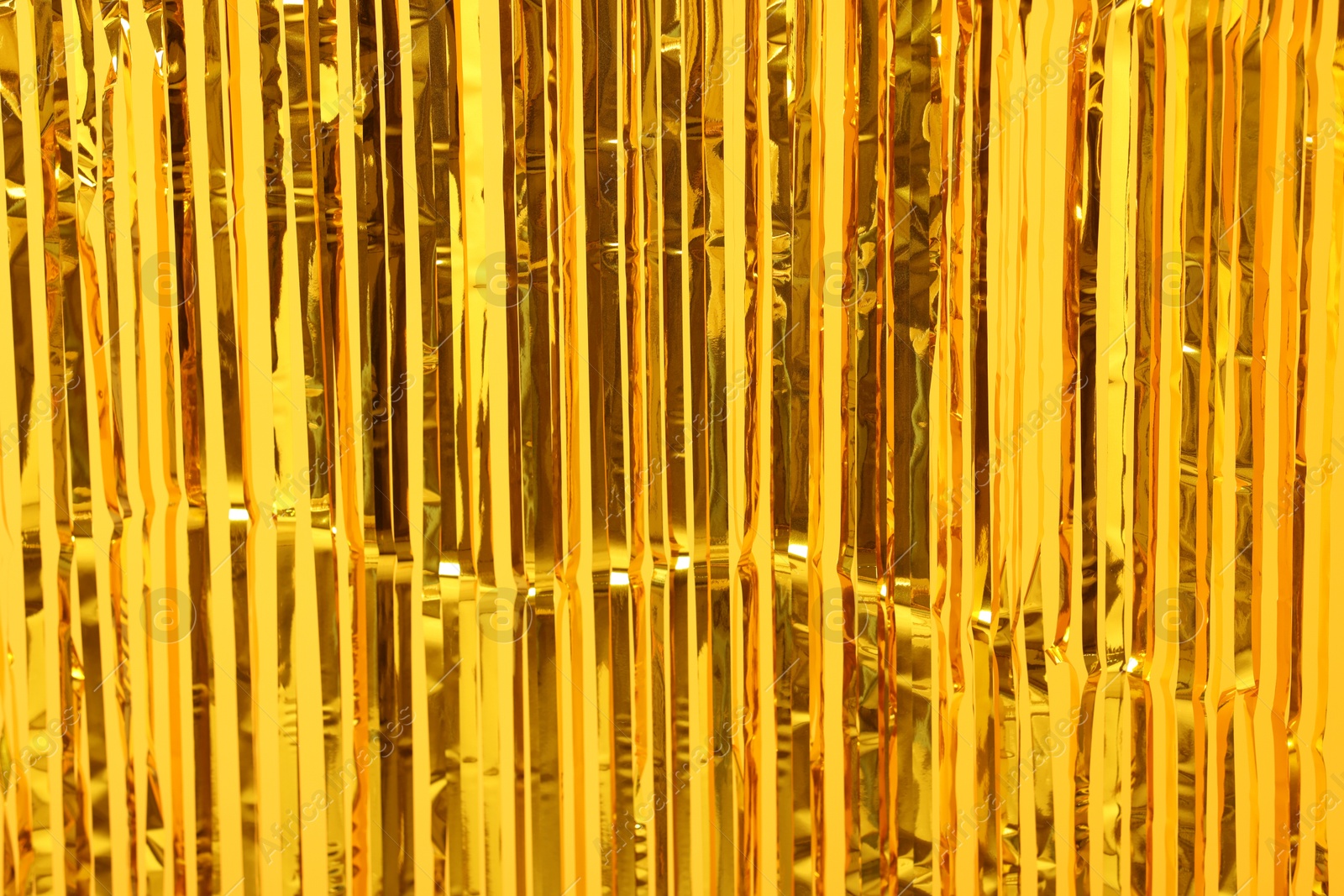 Photo of Golden foil curtain as background, closeup view