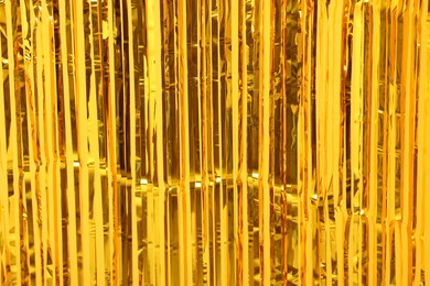 Photo of Golden foil curtain as background, closeup view