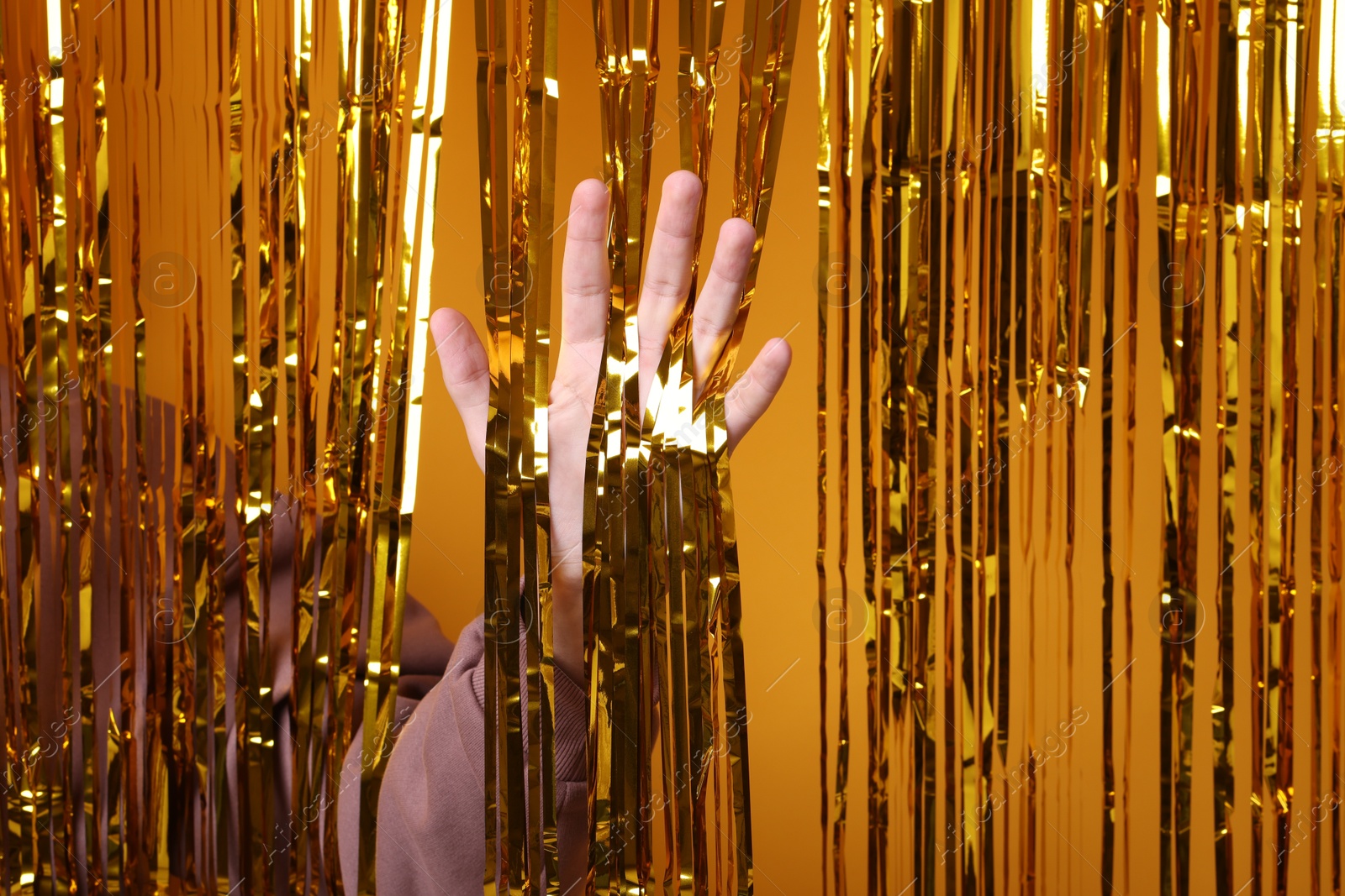 Photo of Man near golden foil curtain against orange background, closeup