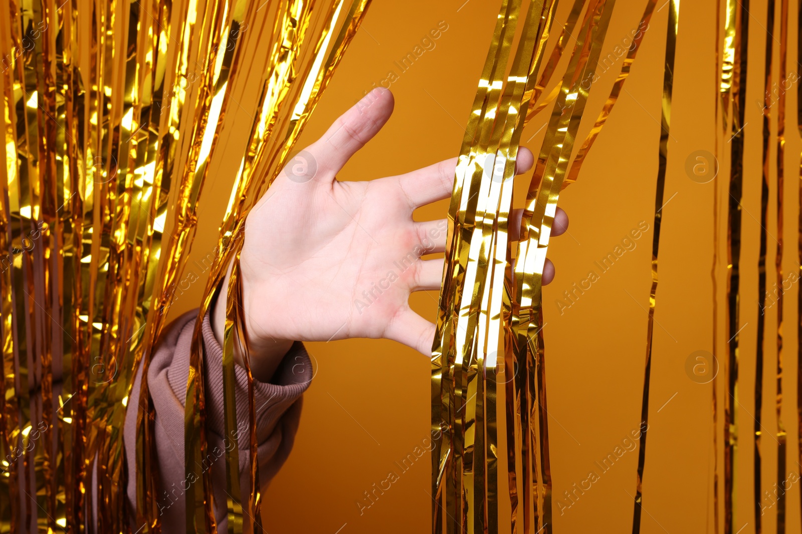 Photo of Man near golden foil curtain against orange background, closeup