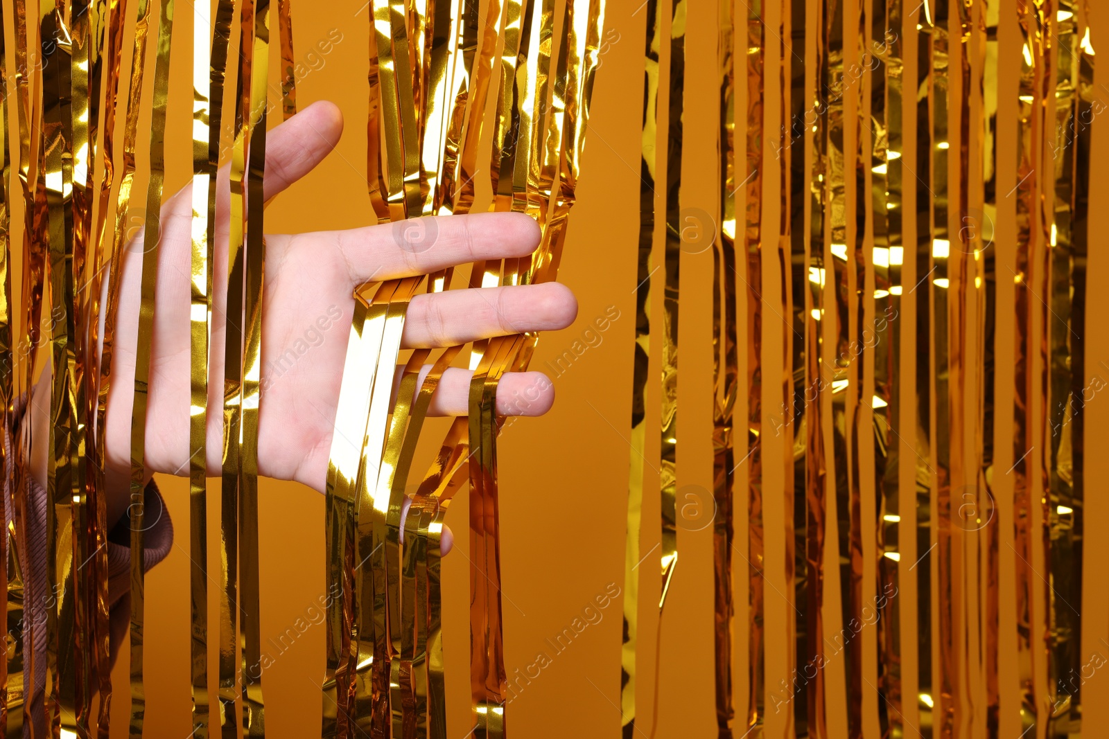 Photo of Man near golden foil curtain against orange background, closeup