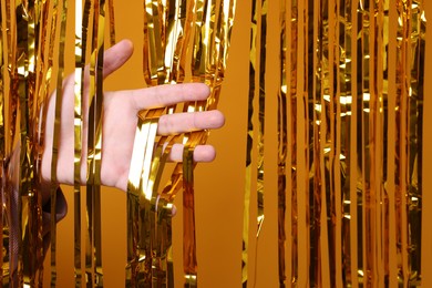 Photo of Man near golden foil curtain against orange background, closeup