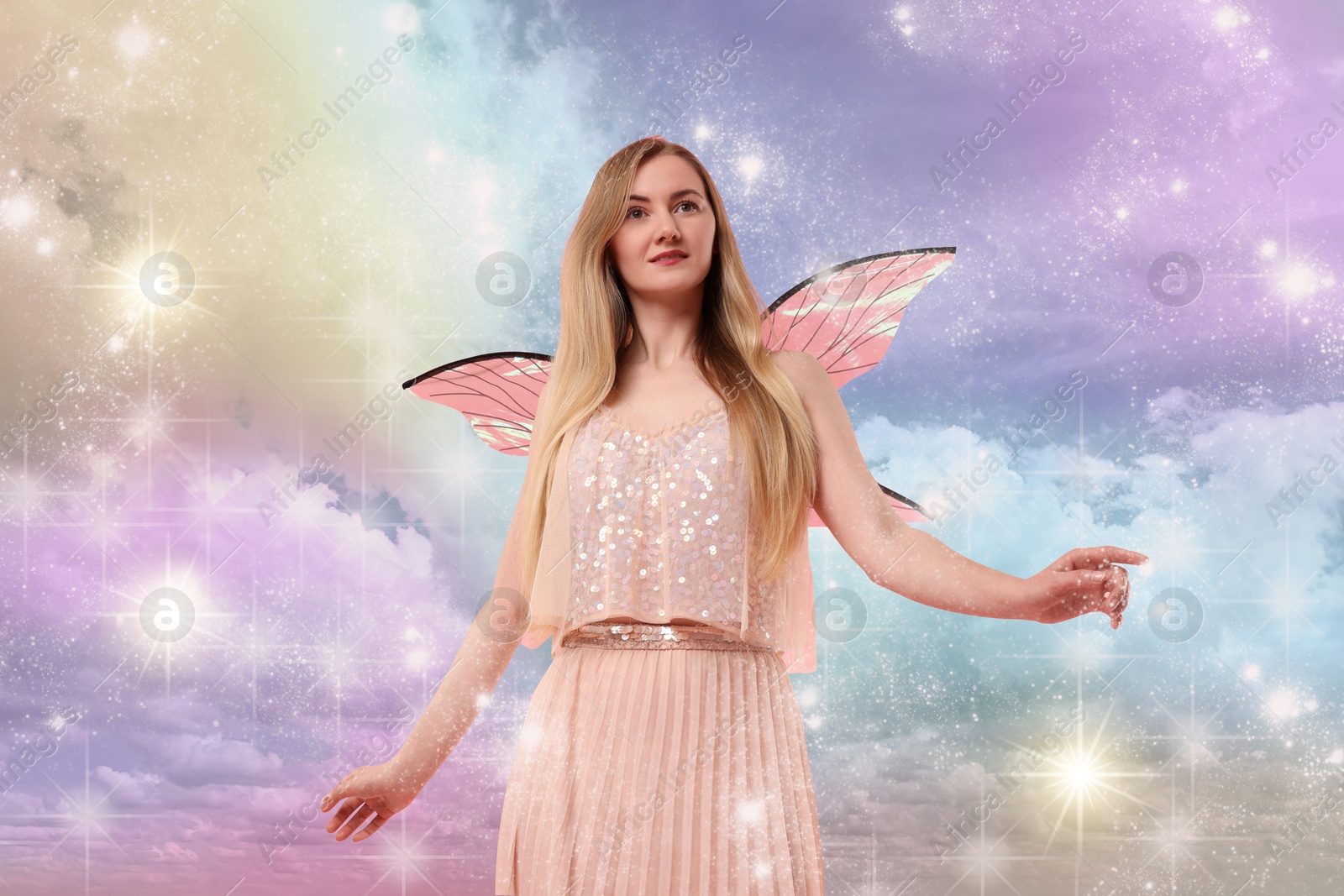 Image of Ethereal fairy under fluffy clouds in colorful sky. Beautiful girl with wings among magic lights